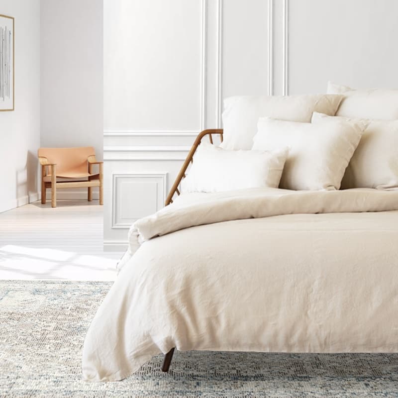 Ein Beige weißes Bett mit Decke und mehrere Kissen